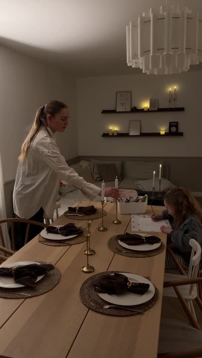 Tændte stearinlys på et dækket bord i en dæmpet stue